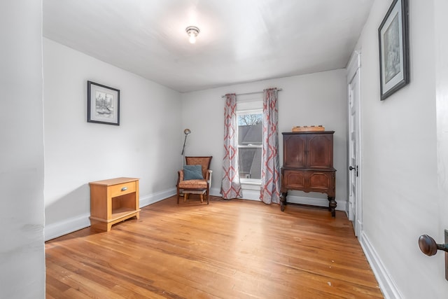 sitting room featuring baseboards and light wood finished floors