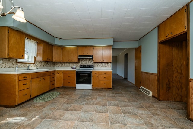 kitchen with visible vents, a wainscoted wall, range with electric cooktop, under cabinet range hood, and brown cabinetry