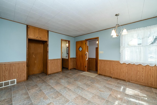 spare room featuring visible vents, wooden walls, and wainscoting