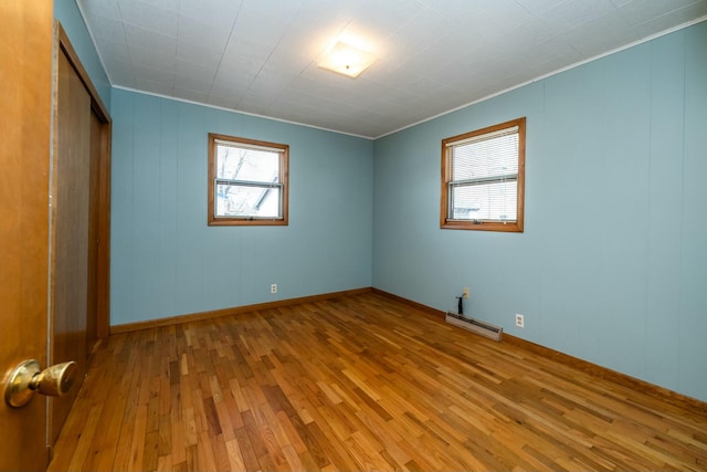 unfurnished bedroom with a closet, hardwood / wood-style floors, and a baseboard radiator