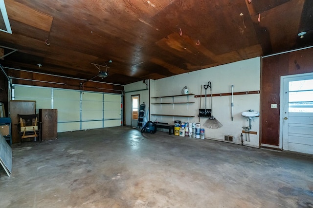 garage featuring wood ceiling, a garage door opener, and visible vents