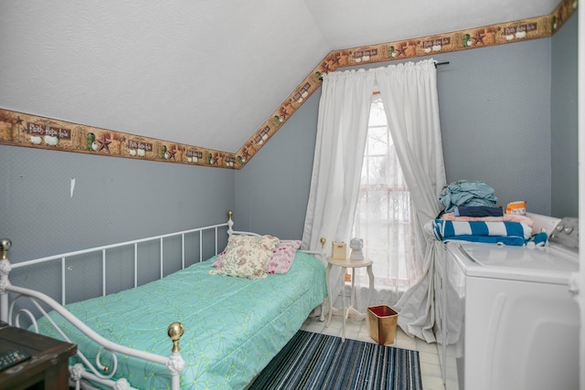 bedroom with washer and dryer, lofted ceiling, tile patterned floors, and wallpapered walls