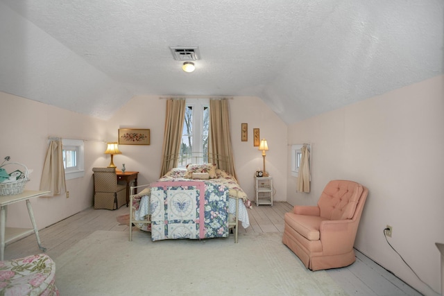 bedroom with visible vents, lofted ceiling, and a textured ceiling