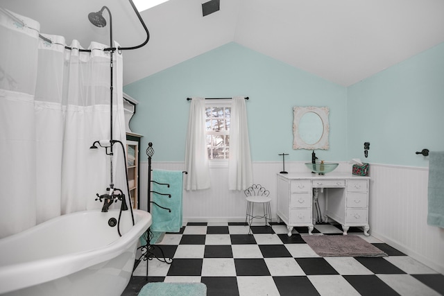 bathroom with tile patterned floors, a soaking tub, a wainscoted wall, and vaulted ceiling