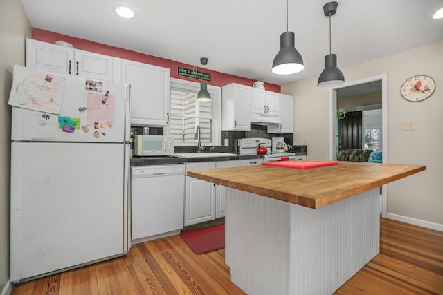 kitchen with white appliances, a sink, butcher block countertops, white cabinets, and under cabinet range hood