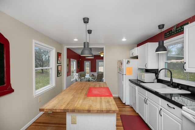 kitchen featuring a sink, a center island, white appliances, light wood-style floors, and white cabinets