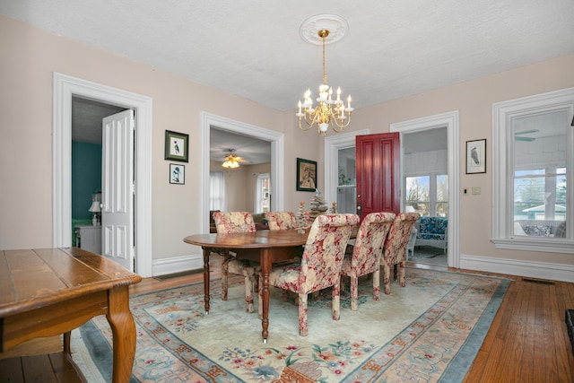 dining space featuring hardwood / wood-style floors, an inviting chandelier, visible vents, and baseboards