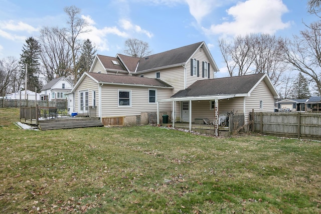 rear view of house featuring a wooden deck, a yard, and fence