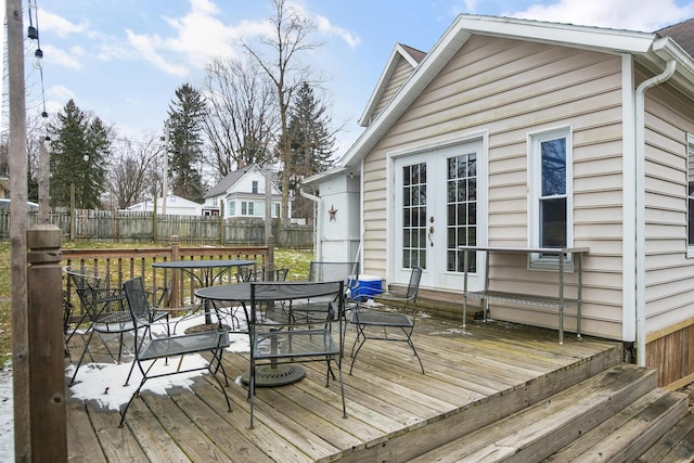 deck featuring outdoor dining area, french doors, and fence