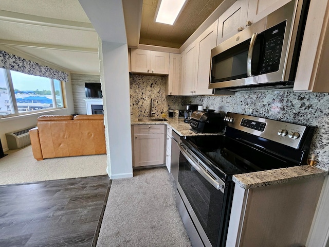 9059 Clam Lake Rd, Bellaire, MI 49615 - kitchen featuring a sink, appliances with stainless steel finishes, a fireplace, decorative backsplash, and light stone countertops