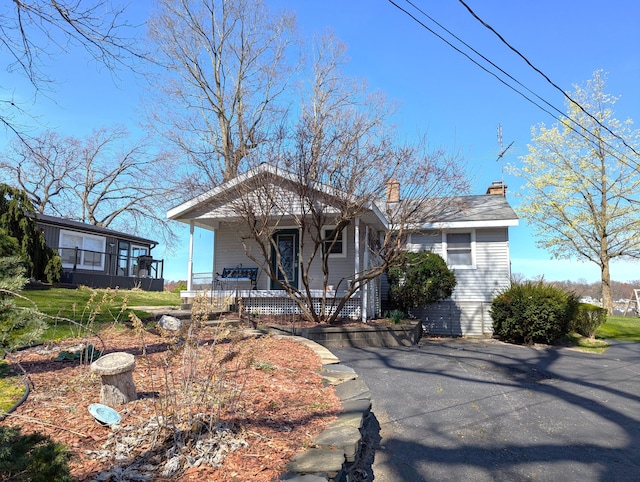 view of front of home featuring a chimney and covered porch