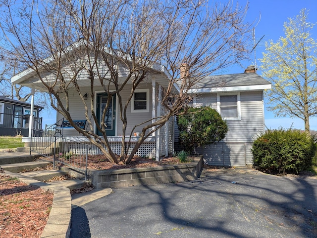 view of front of home featuring a chimney and a porch
