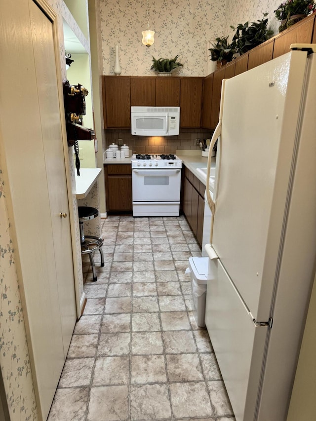 kitchen with white appliances, wallpapered walls, decorative backsplash, light countertops, and brown cabinets