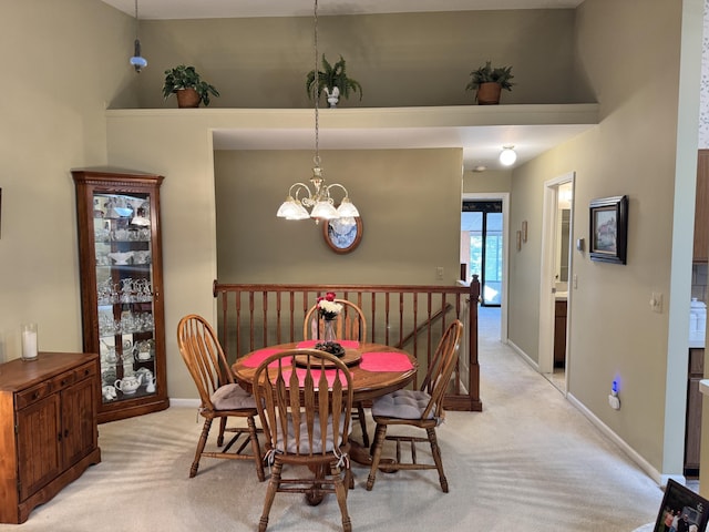 dining room with light colored carpet, baseboards, and a chandelier