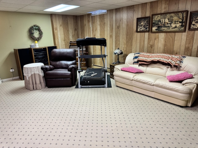 living area featuring wooden walls, a drop ceiling, baseboards, and carpet floors