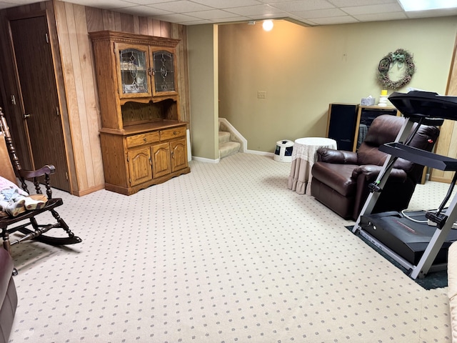 exercise area with wooden walls, a paneled ceiling, baseboards, and light carpet