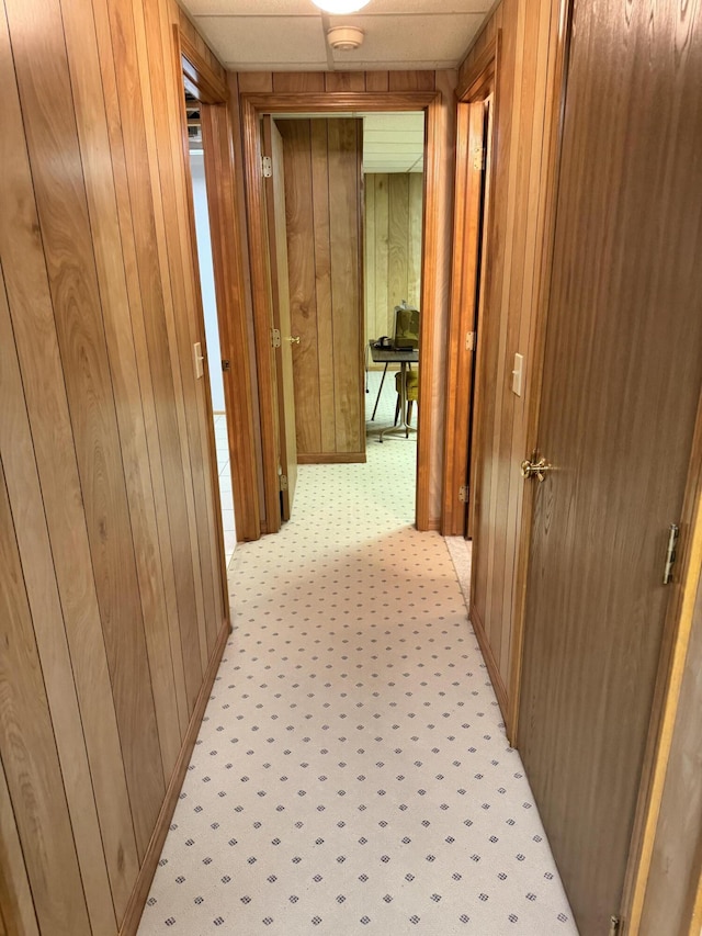 hall with light colored carpet and wood walls