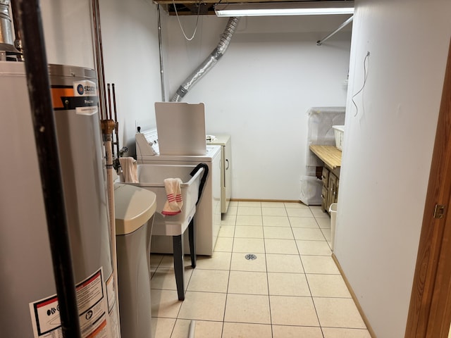 washroom featuring baseboards, laundry area, light tile patterned flooring, water heater, and washer and clothes dryer