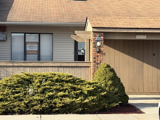 view of side of property with roof with shingles