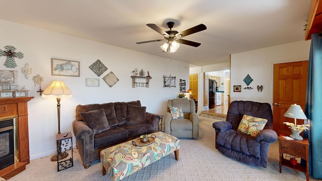 carpeted living area featuring a glass covered fireplace, a ceiling fan, and baseboards