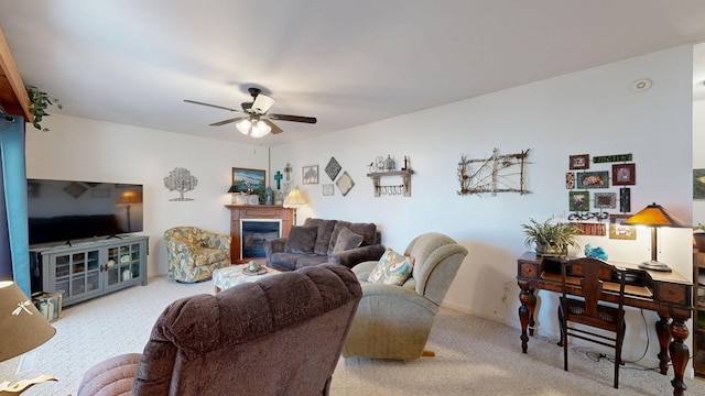 carpeted living room featuring a glass covered fireplace, baseboards, and a ceiling fan