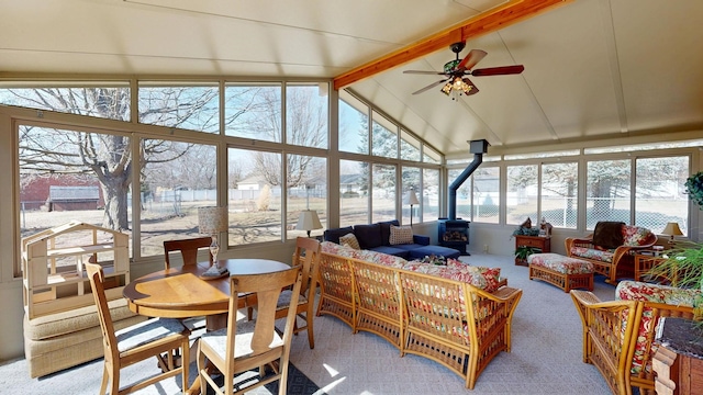 sunroom / solarium with lofted ceiling with beams, a ceiling fan, and a wood stove