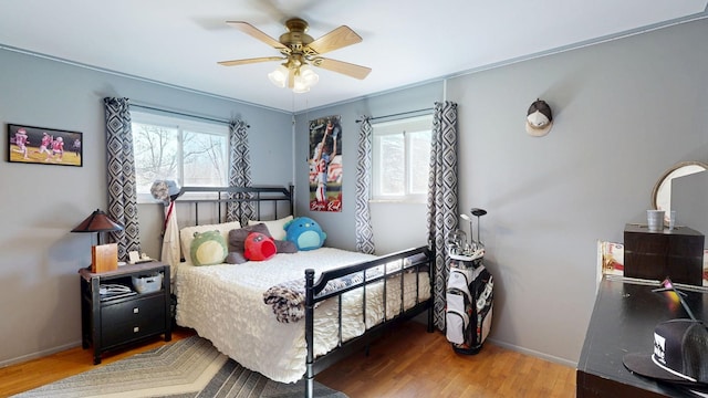 bedroom with ceiling fan, baseboards, and wood finished floors