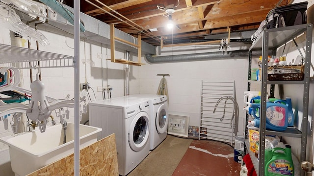 laundry room featuring a sink, concrete block wall, washing machine and dryer, and laundry area