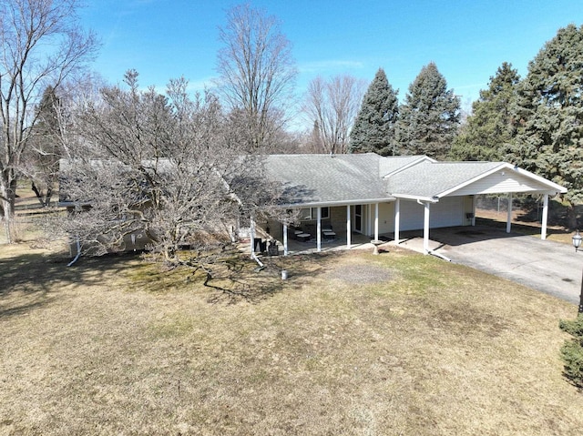 view of front of house featuring an attached carport, a front yard, driveway, and a shingled roof