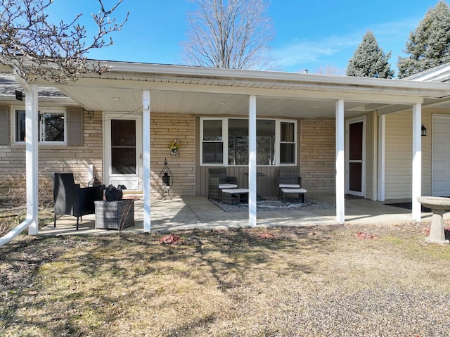 rear view of house featuring brick siding and covered porch