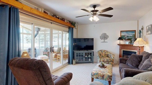 living room with a glass covered fireplace, a ceiling fan, and carpet floors