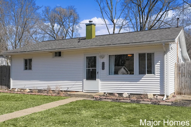 view of front facade with a shingled roof, a front lawn, fence, and a chimney