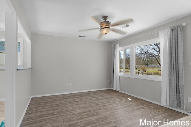 spare room with baseboards, wood finished floors, visible vents, and ceiling fan