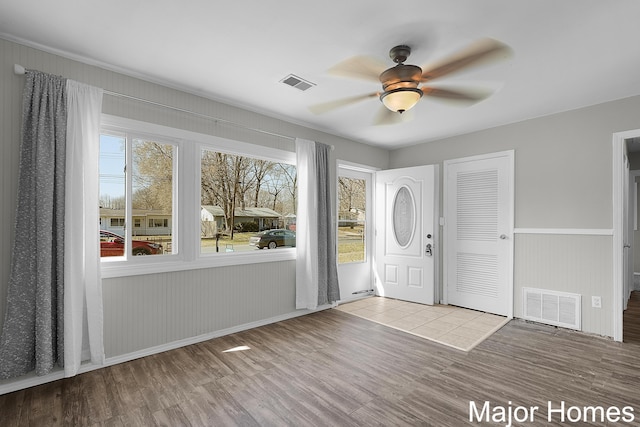 foyer entrance with visible vents, a wainscoted wall, ceiling fan, and wood finished floors