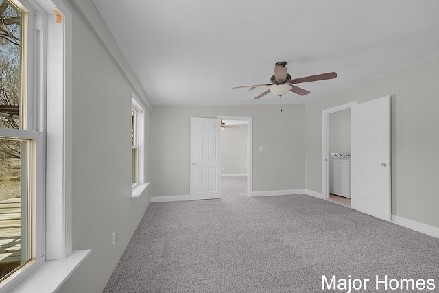 carpeted empty room featuring baseboards, washer / dryer, and a ceiling fan