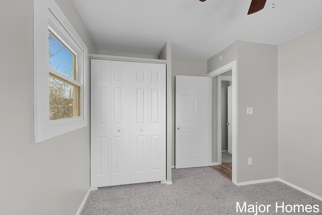 unfurnished bedroom featuring baseboards, carpet floors, a closet, and a ceiling fan