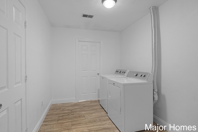 laundry area featuring light wood finished floors, visible vents, baseboards, laundry area, and separate washer and dryer