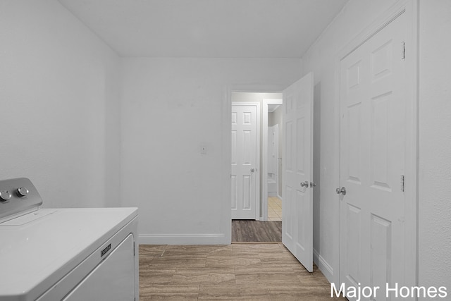 clothes washing area featuring light wood finished floors, laundry area, washer / clothes dryer, and baseboards