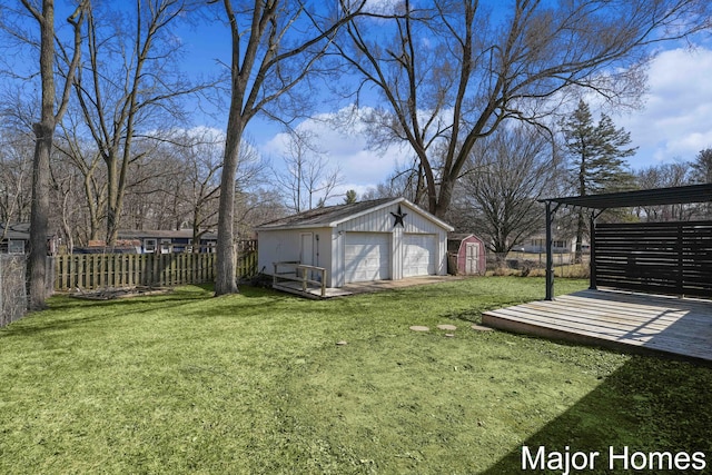 view of yard with a garage, an outbuilding, and fence