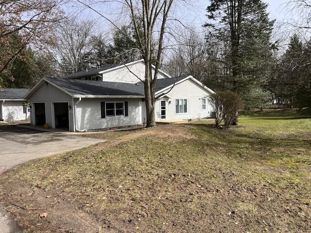 single story home featuring a front lawn, an attached garage, and driveway