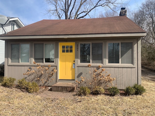 view of front of property with roof with shingles and a chimney