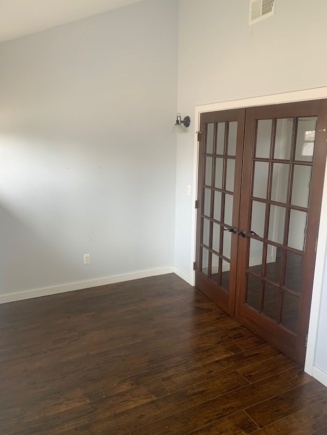 empty room with dark wood finished floors, french doors, visible vents, and baseboards