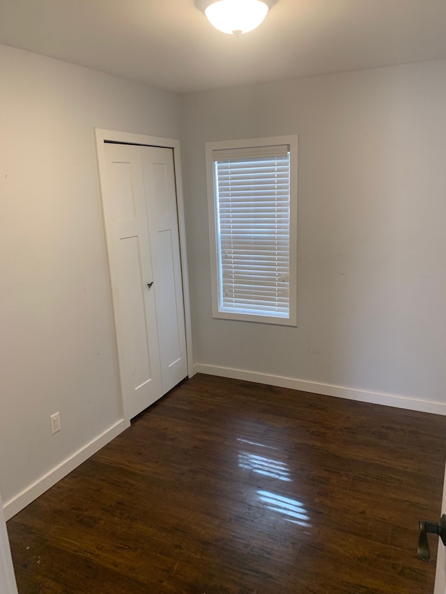 unfurnished room with dark wood-style floors and baseboards