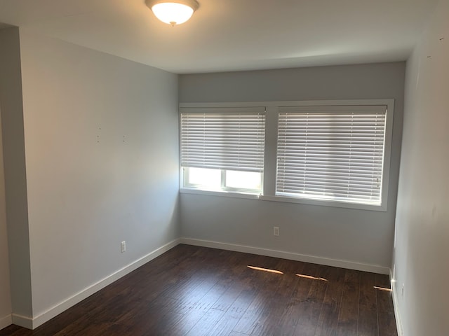 empty room featuring dark wood-type flooring and baseboards