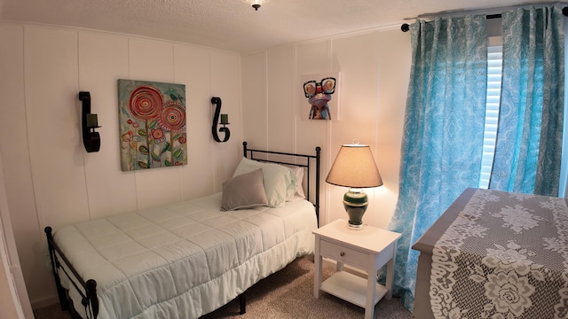 carpeted bedroom with a decorative wall and a textured ceiling