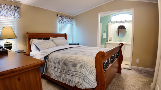 bedroom with crown molding, baseboards, light colored carpet, lofted ceiling, and ensuite bath