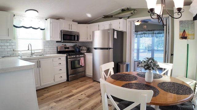 kitchen featuring a sink, stainless steel appliances, light countertops, decorative backsplash, and lofted ceiling