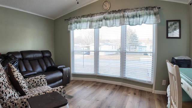 living area featuring plenty of natural light, light wood-style flooring, crown molding, and vaulted ceiling