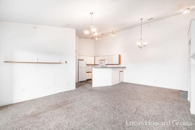 kitchen featuring open floor plan, white appliances, carpet, a peninsula, and a chandelier