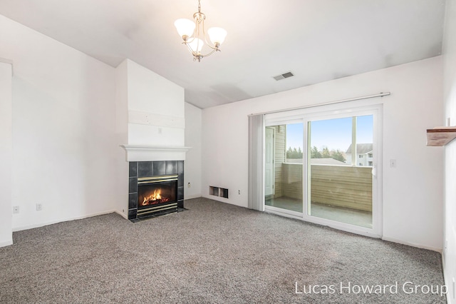 unfurnished living room featuring visible vents, lofted ceiling, a fireplace, carpet flooring, and a chandelier